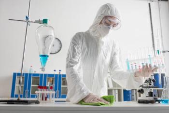 doctor in protective suit holding test tubes while wiping desk in laboratory. | Image Credit: © LIGHTFIELD STUDIOS - stock.adobe.com