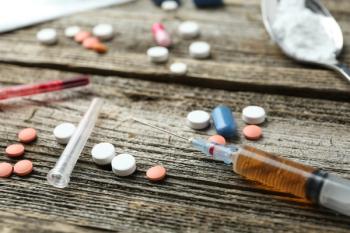 Drug addiction. Syringe and pills on wooden table, closeup | Image Credit: © New Africa - stock.adobe.com