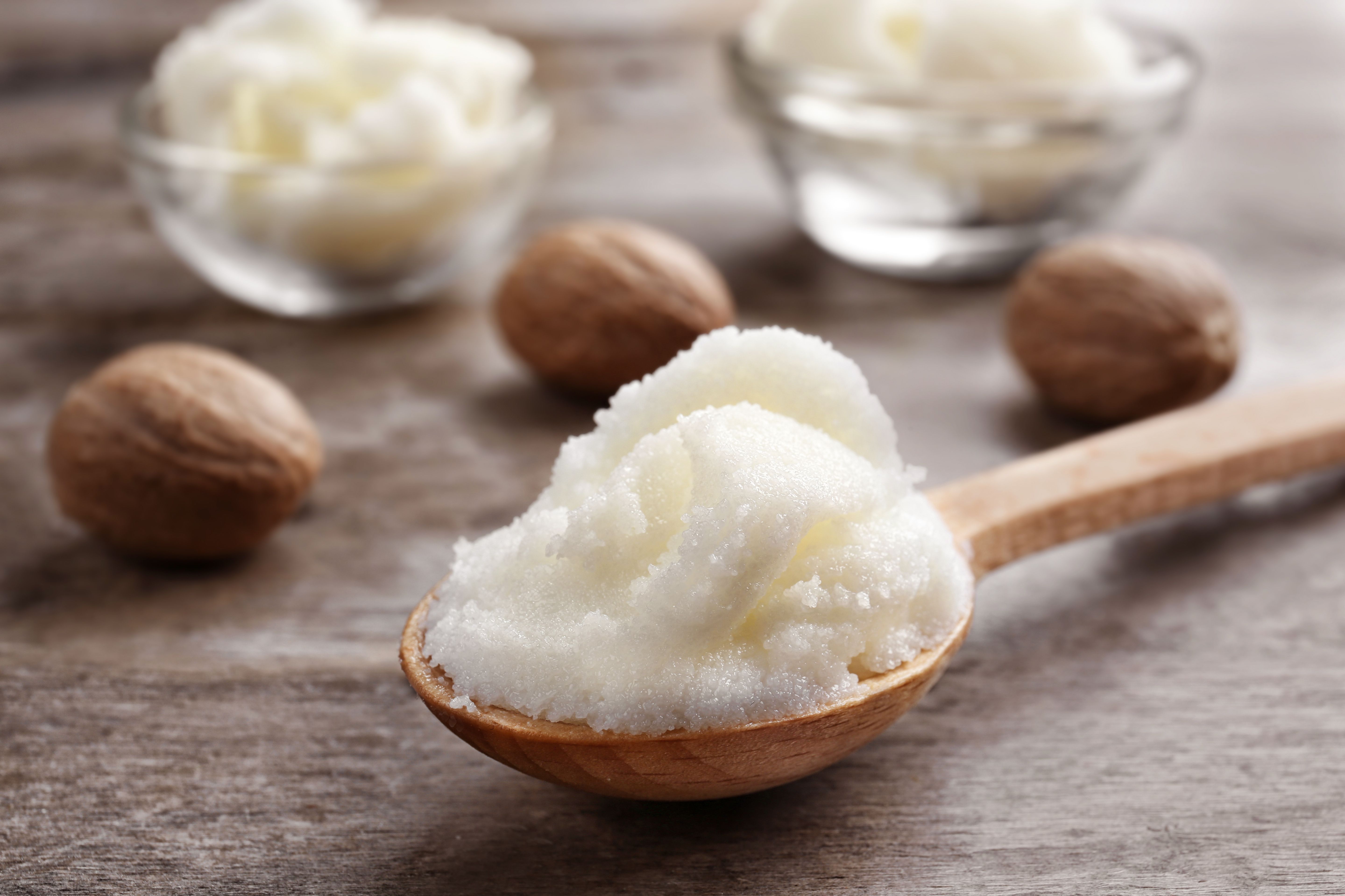 Shea butter in spoon and bowls on wooden background, close up | Image Credit: © Africa Studio - stock.adobe.com