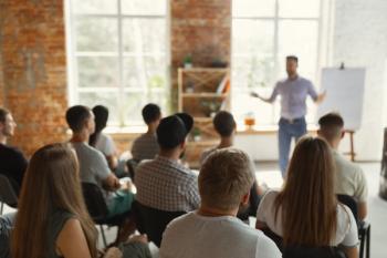 Male speaker giving presentation in hall at university workshop. Audience or conference hall. Rear view of unrecognized participants in audience. Scientific conference event, training. Education | Image Credit: © master1305 - stock.adobe.com