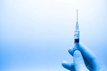 gloved hand holding syringe