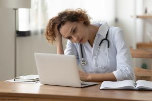 Stressed young female doctor looking at laptop reading bad news online worried of mistake at workplace. Unhappy professional physician in tension feeling tired solving computer problem at work | Image Credit: © fizkes – stock.adobe.com