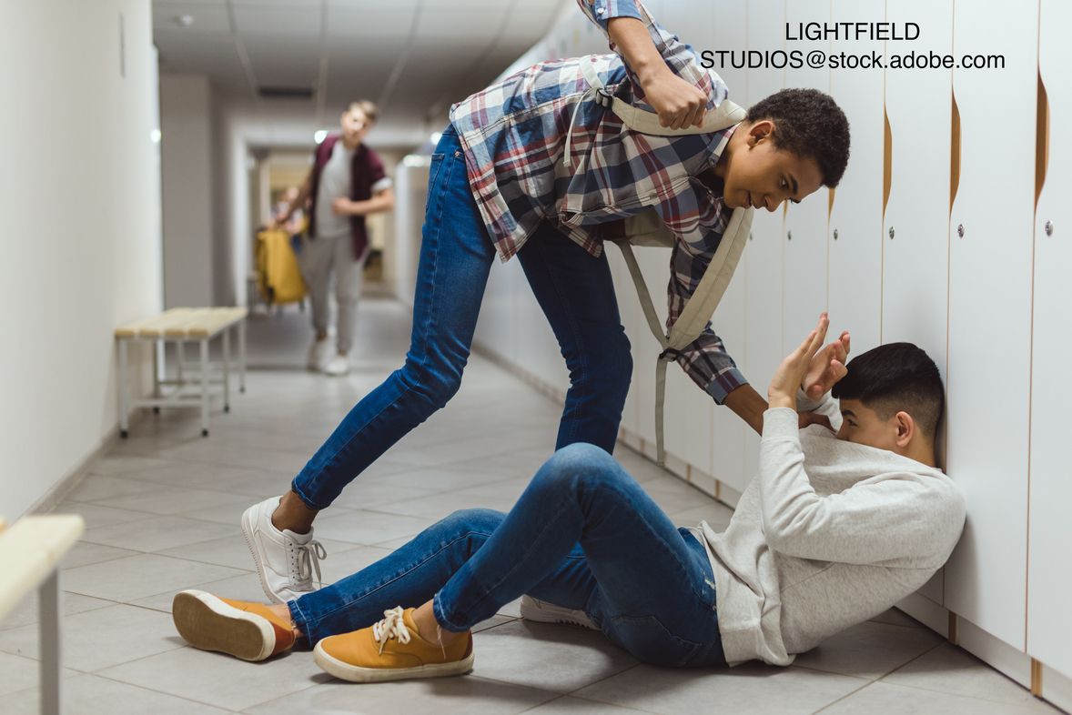 image of teen bullying a teen in a school hallway