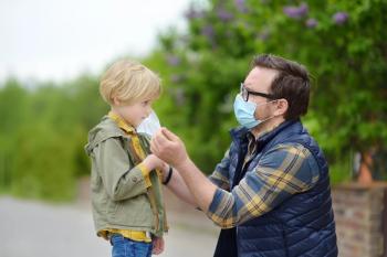 Adult putting mask on child outside | Image Credit: © Maria Sbytova - © Maria Sbytova - stock.adobe.com.