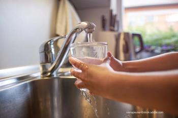 child getting a class of water from the faucet