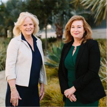 Kerry O’Neil, B.S.N., RN, OCN (left), wearing a blue dress and white blazer, smiles next to Cynthia Powers, D.N.P., M.S.N., RN, CPHQ (right), wearing a green dress and black blazer