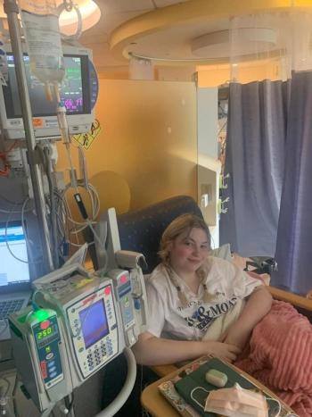 Image of a woman with two braids sitting in a hospital bed.