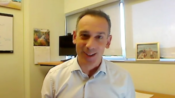 Image of a man with short hair, wearing a buttoned-up shirt.
