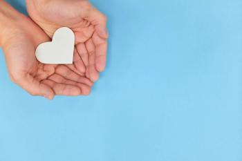 Image of a pair of hands holding a paper heart. 