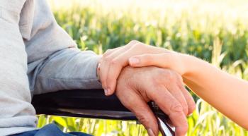 Image of a patient in a wheel chair with their caregiver beside them.