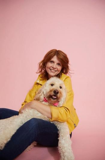 Image of a woman wearing a yellow leather jacket, hugging a dog.
