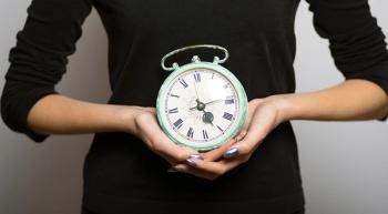 Image of a person holding an analog clock.