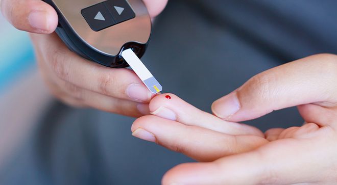 person pricking their finger and using a glucose monitor