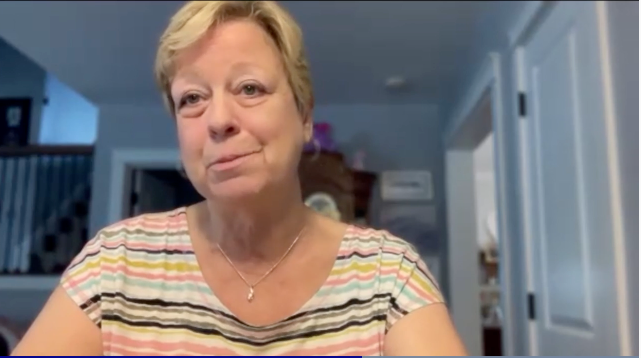 Image of a woman with short blonde hair, wearing a colorful striped shirt.