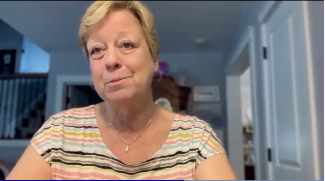 Image of a woman with short blonde hair, wearing a colorful striped shirt. 