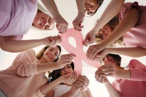 Image of women holding the symbol for breast cancer awareness, the pink ribbon.
