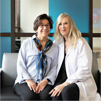 Image of two women sitting on a couch and smiling. 