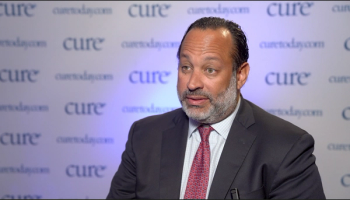 Dr. Pierre de Delva speaking in front of a CURE backdrop