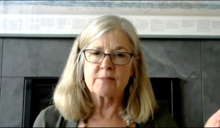 Image of a woman with light shoulder-length hair, wearing rectangular glasses.