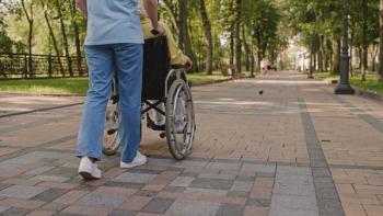 Image of a person pushing a patient in a wheelchair. 