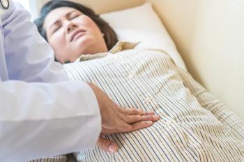 Doctor examining stomach of woman patient and pressing hands on her belly. | Image credit: © Pormezz - © stock.adobe.com