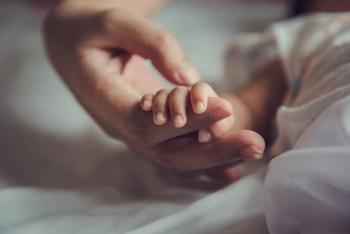 Image of an adult holding a small child's hand in the hospital. 
