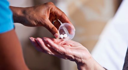 Image of a doctor giving two pills to a patient.