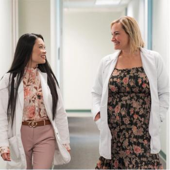 From left: CLARESSA ROSACINA, M.S.N., AGNP-BCP, and AFTON DICKERSON, M.S.N., ACAGNP-BCP, CBCN  PHOTOS BY DIANA CHAVEZ; the two women are walking down a hospital hall smiling at each other. Photos by Diana Chaves