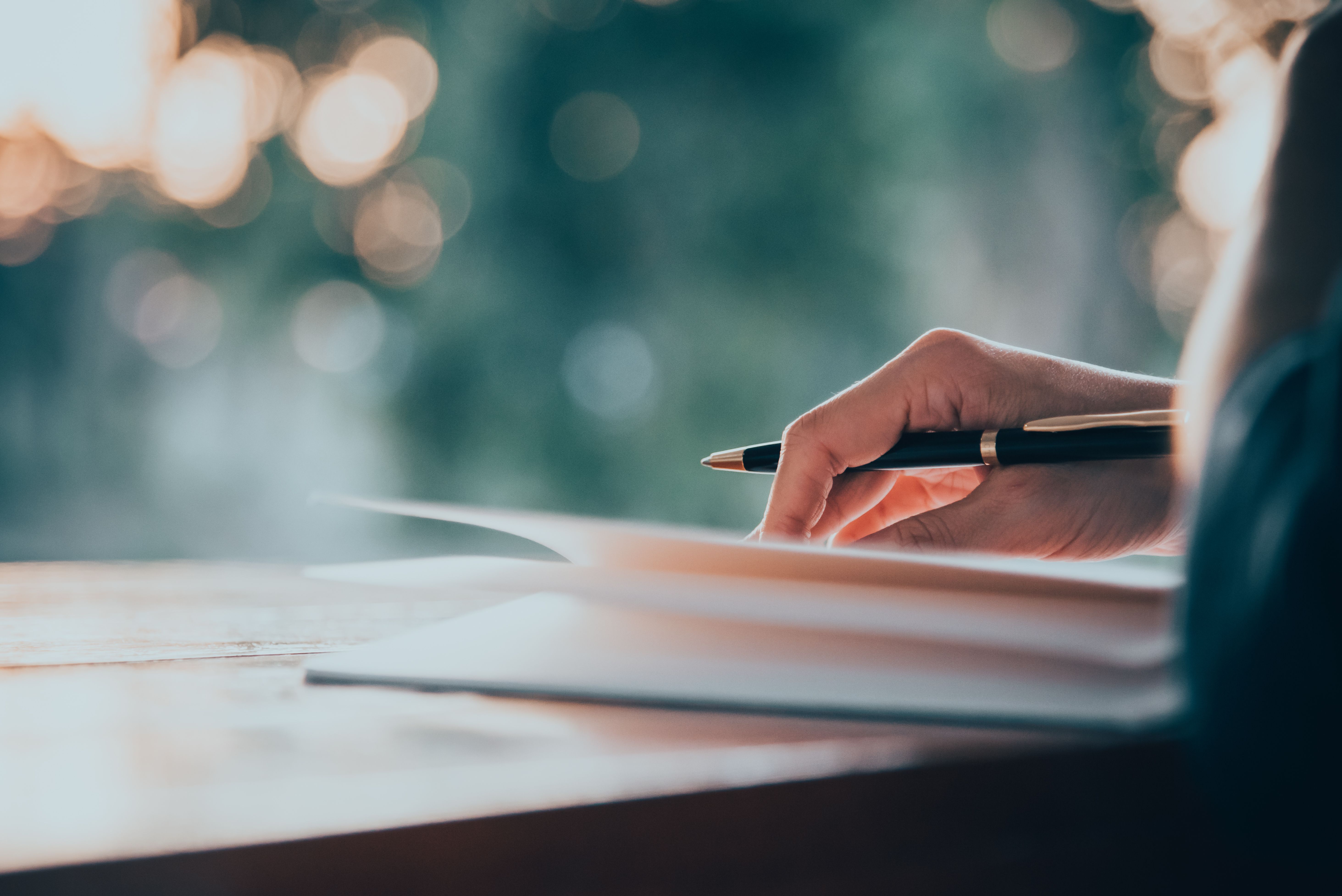 female hand holding a pen, ready to write in an open journal