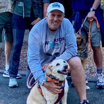 Prostate cancer survivor, Ted Healy, kneeling down and petting his dog