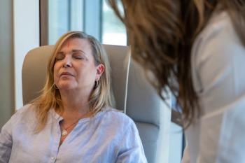Diane Miller sitting in a chair with closed eyes. She has acupuncture needles in her head and ear