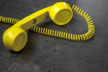 yellow corded phone on a gray background