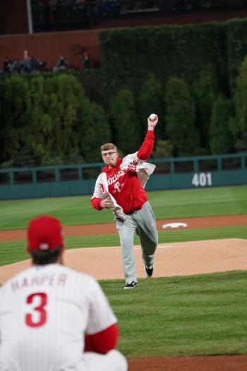 Cancer survivor Luke Theodosiades, dressed in Phillies' gear, standing in front of the pitcher's mound, throwing out the first pitch at Game 4 of the World Series