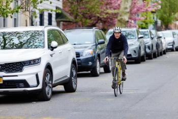 Image of a man in a blue jacket on a bike.