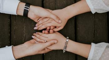 Image of a patient with a caregiver, holding hands.