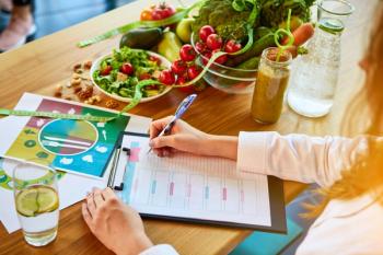 Woman dietitian in medical uniform with tape measure working on a diet plan sitting with different healthy food ingredients in the green office on background. Weight loss and right nutrition concept  | Image credit: © bondvit - © stock.adobe.com