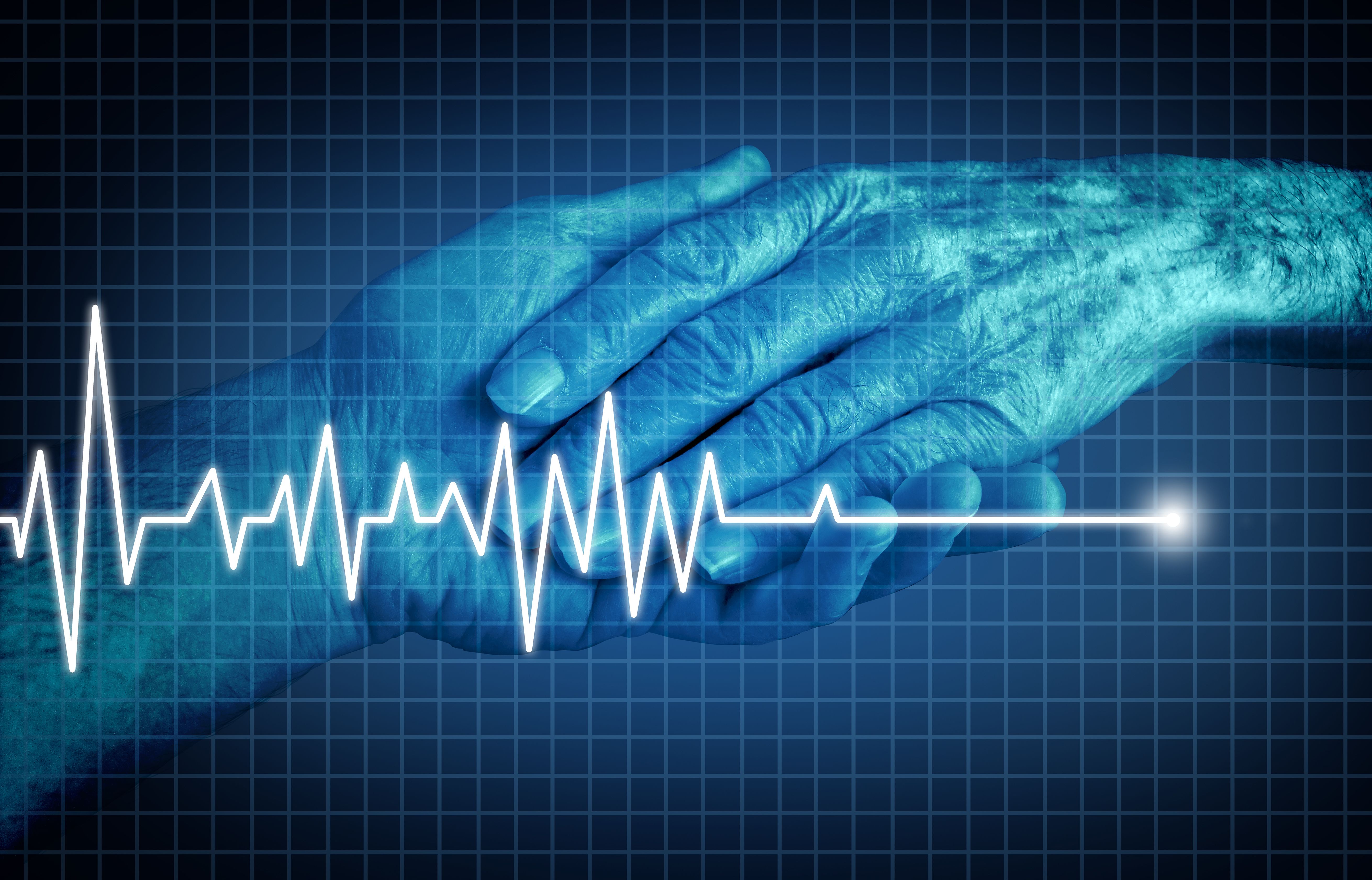 An older man's hand holding a younger man's hand. Over the image is an EKG which is spiking then flatlining