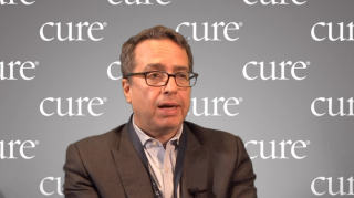 Dr. John Mascarenhas in an interview with a gray background saying "CURE" behind him