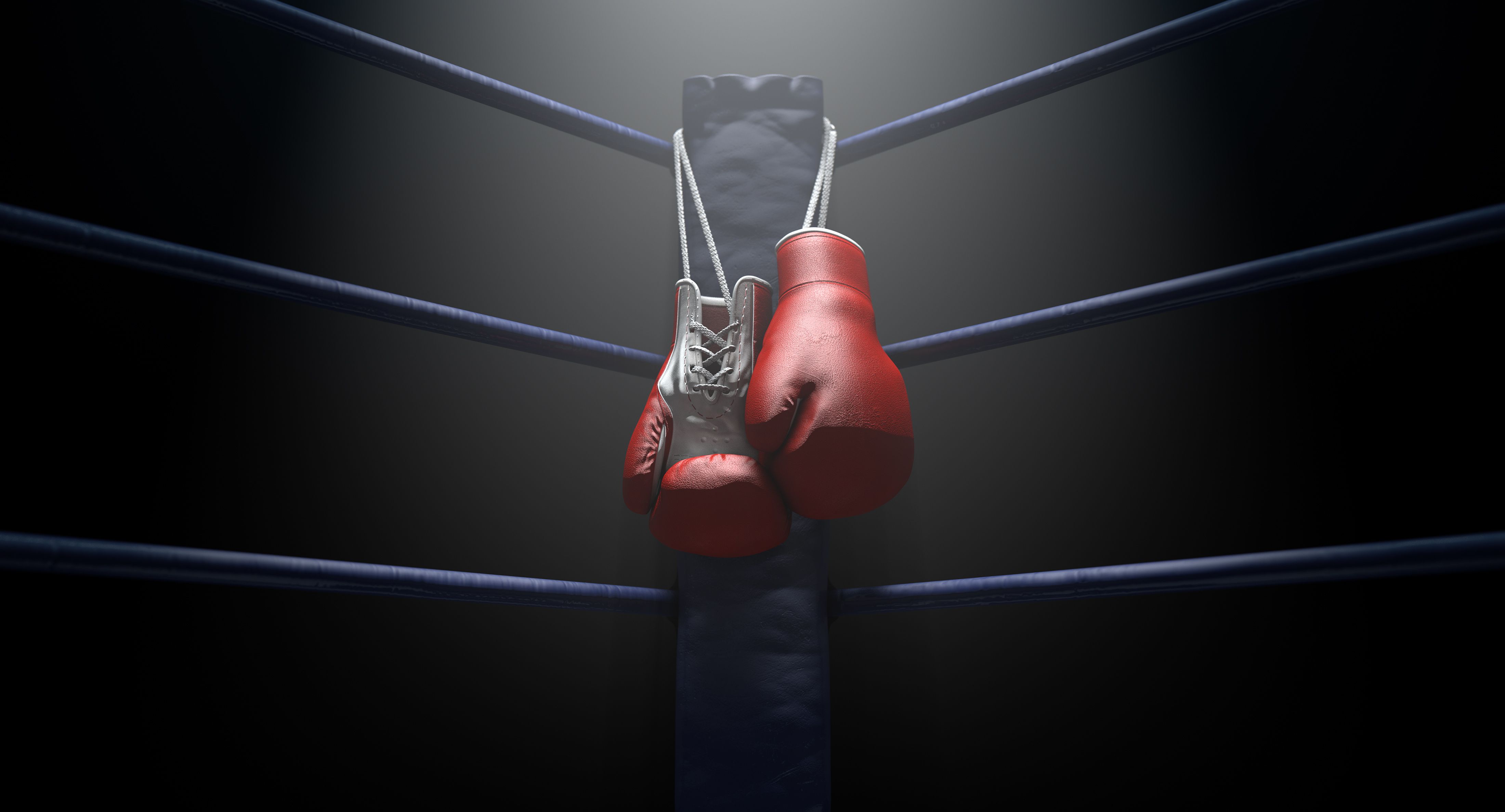 Image of boxing gloves hanging off of a boxing ring. 