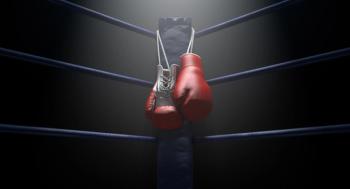 Image of boxing gloves hanging off of a boxing ring. 