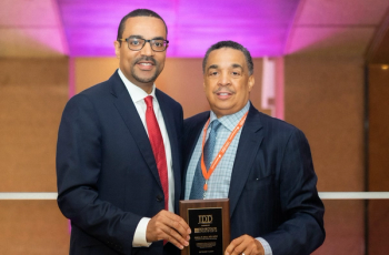 Andrew Alexis, M.D., standing with award