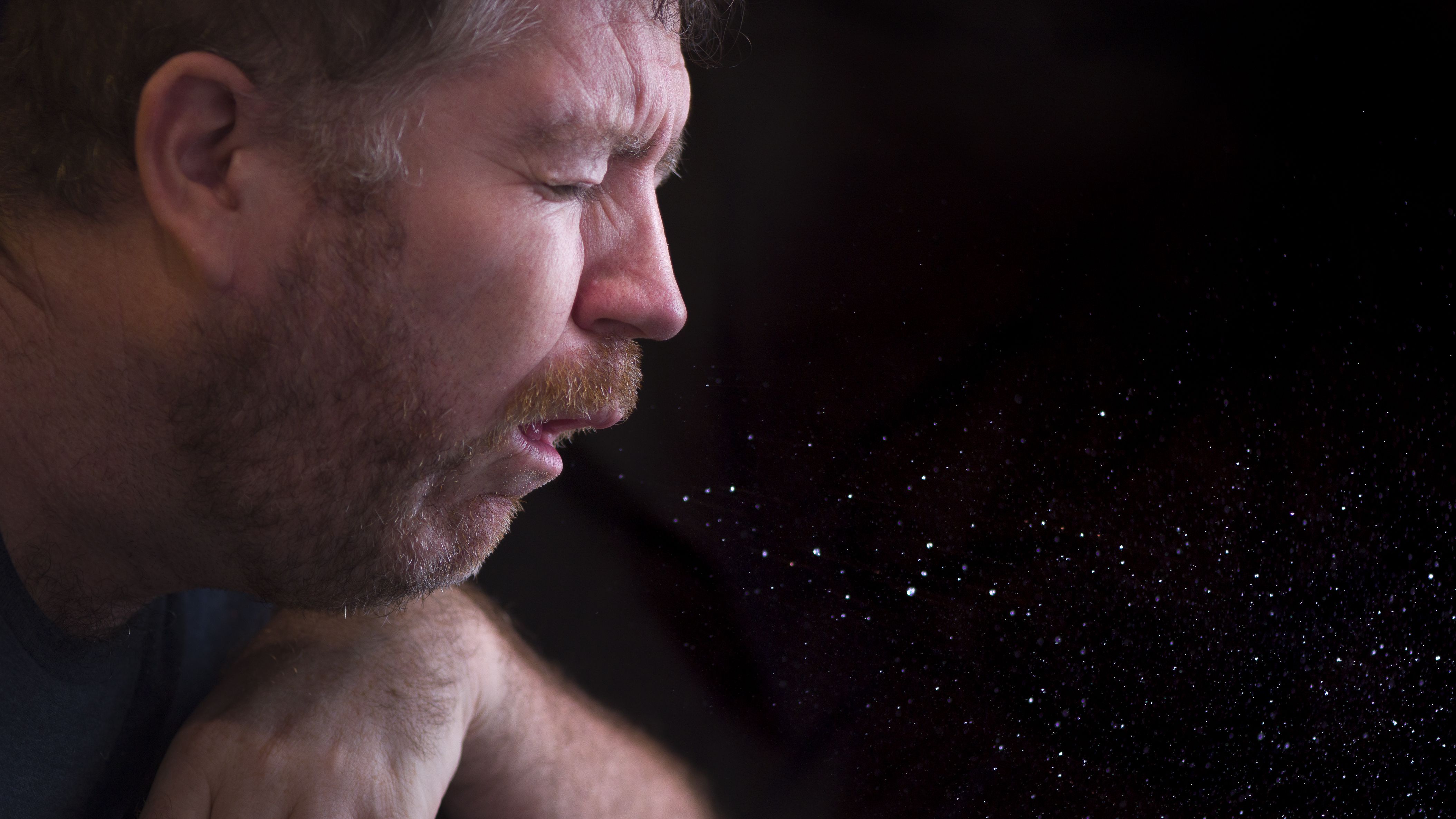 Man sneezing particles in the air