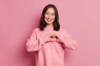 Woman in pink sweater making heart with hands | Image credit: WHstudio Leushin N - stock.adobe.com