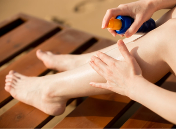 woman spraying aerosol sunscreen 