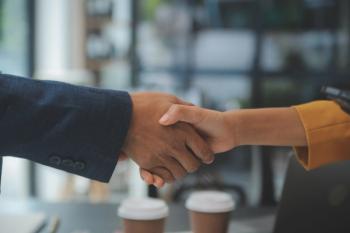 Business professionals shaking hands after entering license and supply agreement