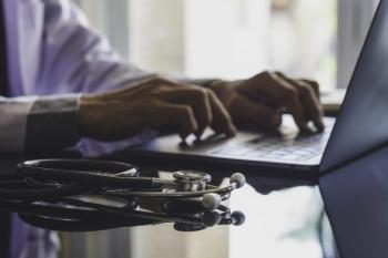 Doctor with stethoscope typing on a laptop 