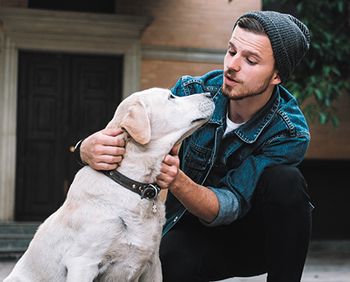 veterinary-the-portrait-of-a-guy-squatting-near-the-golden-labrador-the-guy-is-scratching-dogs-neck-and-talking-to-him-while-this-labrador-is-listening-to-what-his-owner-says-close-up-shutterstock-716932762-body-1.jpg