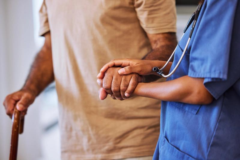 Care provider holding the hand of an aging patient with Alzheimer’s disease. | Credit: Adobe Stock