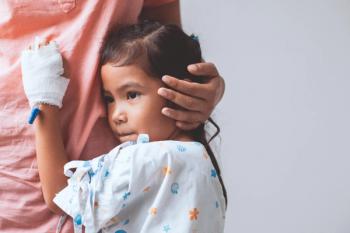 A young girl in a hospital gown. 