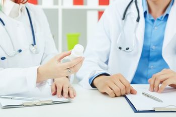 Doctors having a discussion about medications while holding a bottle containing SGLT2 inhibitors.